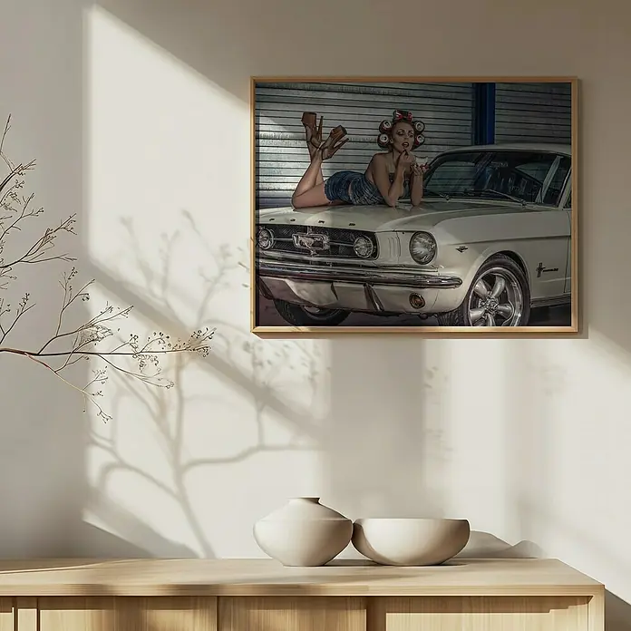 Papermoon Bild - Drive my Car, B x H: 70 x 50 cm, Mit Passepartout, Rahmen Eiche - Ein gerahmtes Foto einer Frau im Pin-up-Stil, die auf einem weißen Oldtimer-Mustang posiert, hängt an einer Wand.
