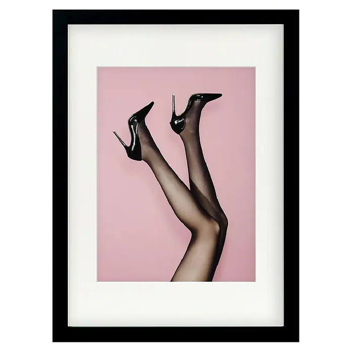 Papermoon Bild - Kick up your Heels, B x H: 40 x 50 cm, Mit Passepartout, Rahmen Schwarz - Gerahmtes Bild von Beinen in Strumpfhosen und schwarzen High Heels vor rosafarbenem Hintergrund, das einen modernen und eleganten Stil zeigt.