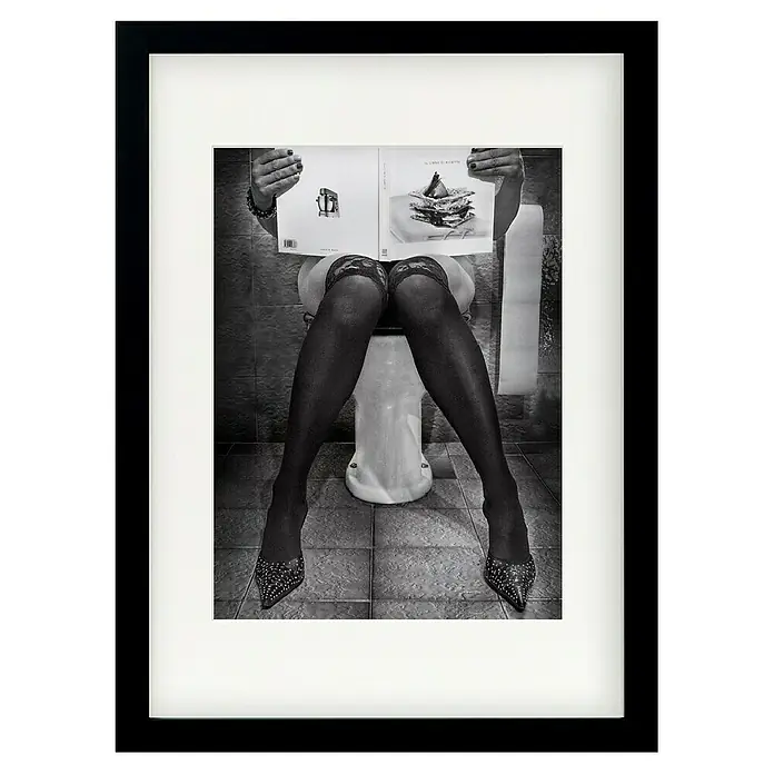 Papermoon Bild - Le Goart des Autres, B x H: 100 x 140 cm, Mit Passepartout, Rahmen Schwarz - Schwarz-Weiß-Foto einer Frau mit halterlosen Strümpfen und High Heels, die auf einer Toilette sitzt und ein Kochbuch liest.