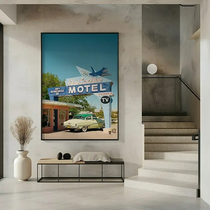 Papermoon Bild - Route 66, B x H: 50 x 70 cm, Mit Passepartout, Rahmen Schwarz - Das Wandbild zeigt das Blue Swallow Motel mit einem Oldtimer davor, gerahmt und an einer stilvollen Wand über einer Bank platziert.