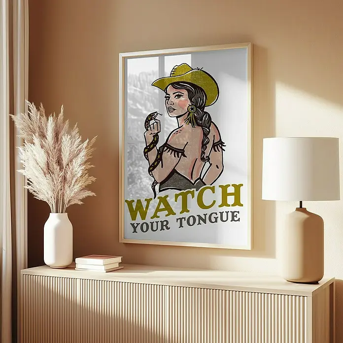 Papermoon Bild - Watch Your Tongue, B x H: 50 x 70 cm, Mit Passepartout, Rahmen Eiche - Ein gerahmtes Poster mit einem Cowgirl und einer Schlange, die zusammen auf einer eleganten Kommode mit Dekorationsgegenständen präsentiert werden.