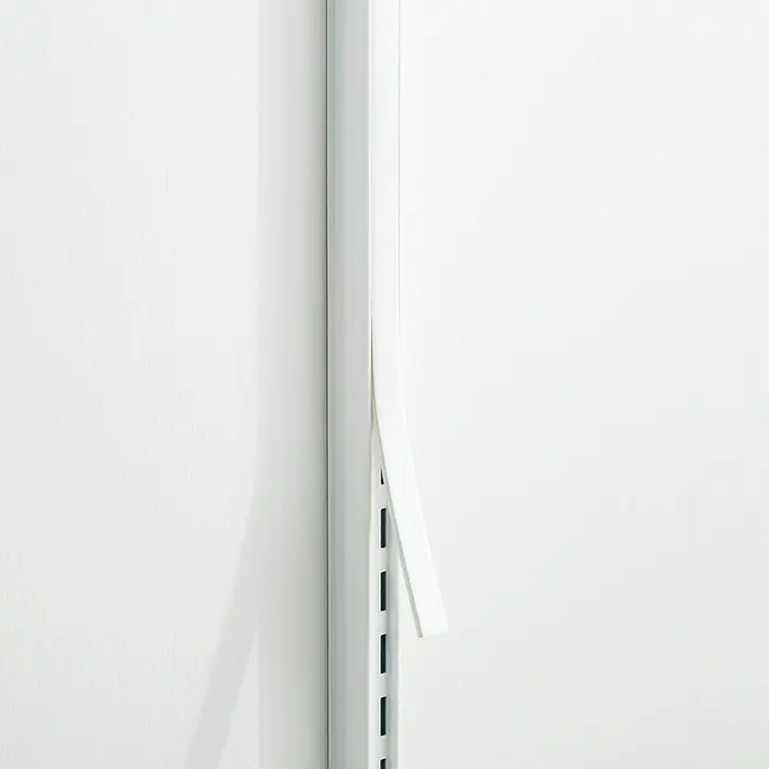 Elfa Garage+/Décor+ by Elfa Abdeckleiste - Höhe: 110 cm, Matt weiß - Ein weißes Regalsystem an einer weißen Wand, wobei ein Teil des Regals leicht absteht und Schatten wirft.