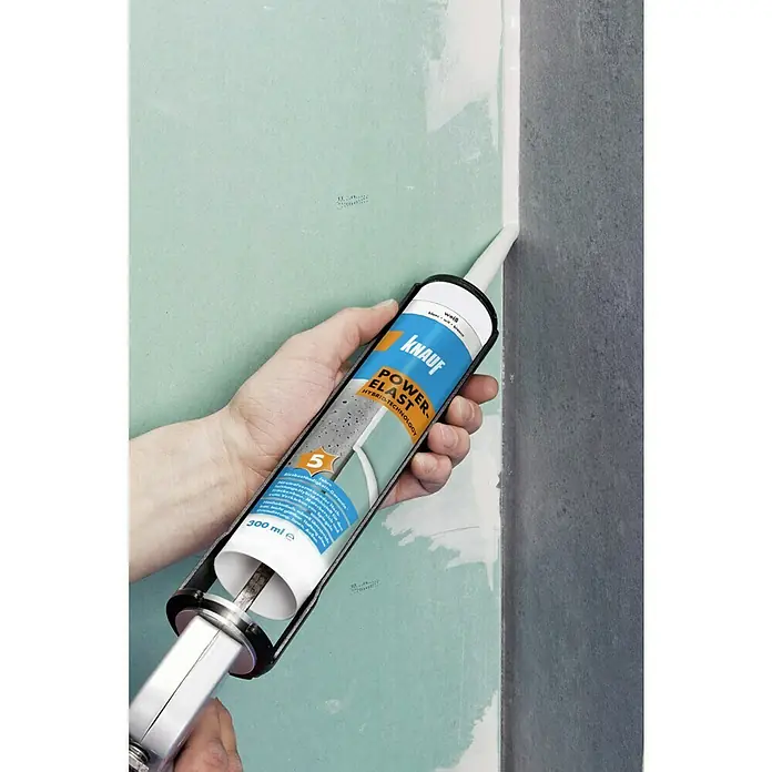 Knauf Dichtstoff Power-Elast - 290 ml, Hybrid-Polymer, Weiß - Auftragen von Knauf Power Elast Hybridtechnologie Dichtstoff aus einer Kartusche mit einer Kartuschenpistole auf einer Wand.
