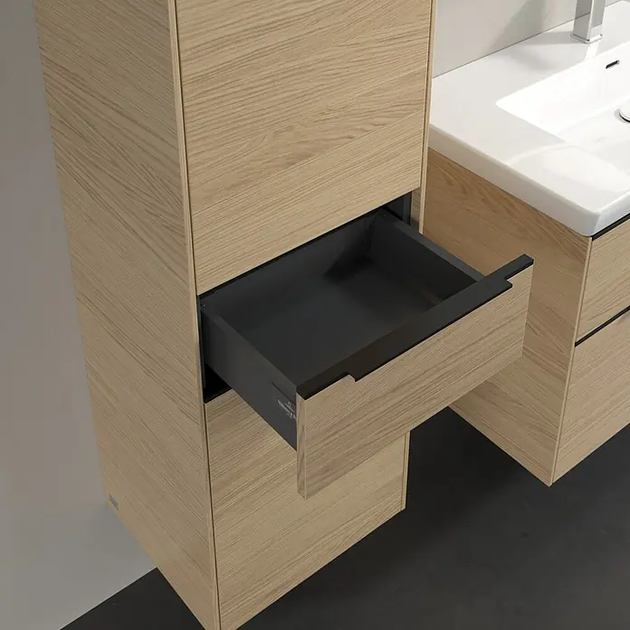 Villeroy & Boch Subway 3.0 Hochschrank - B x T x H: 40 x 36,2 x 171 cm, 1x Schublade, 2x Tür, Nordik oak, Farbe Griff: Volcano black, DIN Anschlag: Links - Aufnahme eines Badezimmerschranks aus hellem Holz mit einer offenen Schublade, die einen Blick auf das dunkle Innere freigibt.
