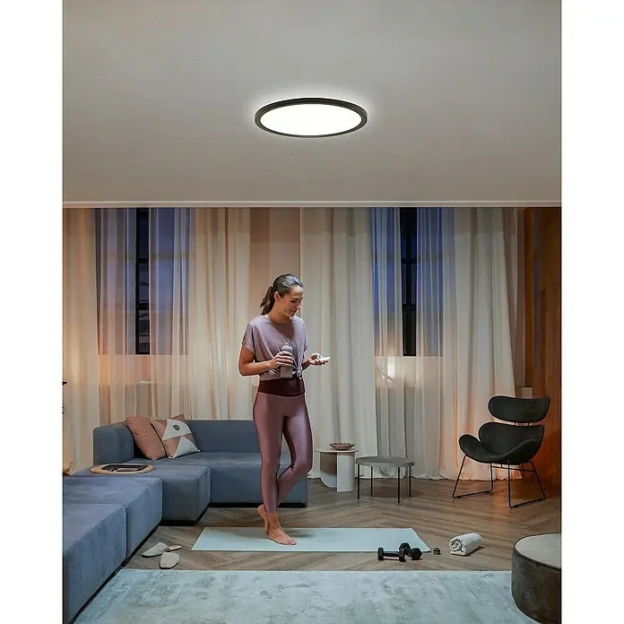 Philips Hue LED-Panel rund White Ambiance Tento XL - 25 W, Ø x H: 54,2 x 3,56 cm, Schwarz, Kaltweiß - Deckenleuchte: Eine moderne, runde LED-Deckenleuchte in einem hellen Raum, die ein angenehmes und gleichmäßiges Licht verbreitet.
