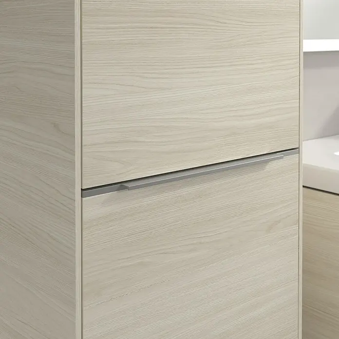 Villeroy & Boch Subway 3.0 Hochschrank - B x T x H: 40 x 36,2 x 171 cm, 1x Klappe mit Wäschekorb, 1x Tür, White Oak, Farbe Griff: Aluminium glänzend, DIN Anschlag: Links - Nahaufnahme eines hellen Holzschranks mit einem eleganten, horizontalen Griff. Das schlichte Design betont die natürliche Maserung des Holzes.