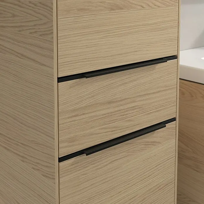 Villeroy & Boch Subway 3.0 Hochschrank - B x T x H: 40 x 36,2 x 171 cm, 1x Schublade, 2x Tür, Nordik oak, Farbe Griff: Volcano black, DIN Anschlag: Links - Nahaufnahme eines Waschtischunterschranks aus Holz mit drei Schubladen und modernen schwarzen Griffen.