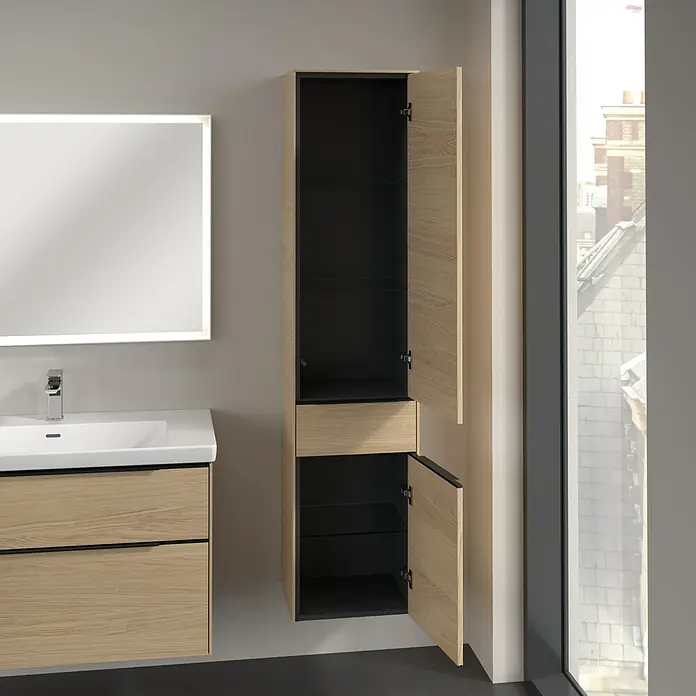 Villeroy & Boch Subway 3.0 Hochschrank - B x T x H: 40 x 36,2 x 171 cm, 1x Schublade, 2x Tür, Nordik oak, Farbe Griff: Volcano black, DIN Anschlag: Rechts - Badezimmeransicht mit einem hellen Holzschrank mit offenen Türen, einem Waschbeckenunterschrank und einem beleuchteten Spiegel.