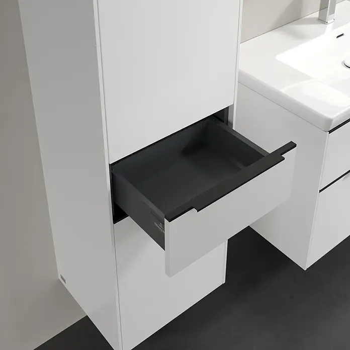 Villeroy & Boch Subway 3.0 Hochschrank - B x T x H: 40 x 36,2 x 171 cm, 1x Schublade, 2x Tür, Pure White, Farbe Griff: Volcano black, DIN Anschlag: Links - Detailaufnahme eines weißen Badezimmerschranks mit offenem Schubfach, das dunkle Innere bietet einen modernen Kontrast zum hellen Äußeren.