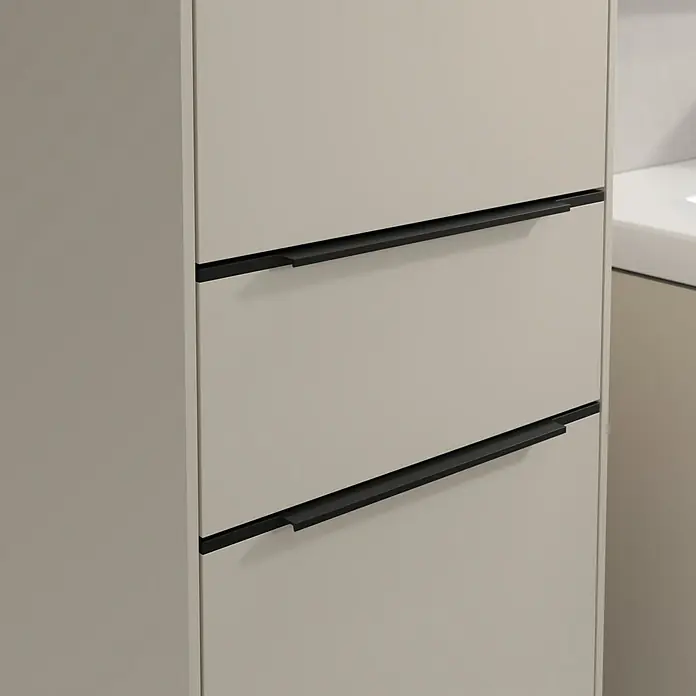 Villeroy & Boch Subway 3.0 Hochschrank - B x T x H: 40 x 36,2 x 171 cm, 1x Schublade, 2x Tür, Cashmere Grey, Farbe Griff: Volcano black, DIN Anschlag: Links - Nahaufnahme eines modernen Badezimmerschranks mit drei Schubladen und schlanken, schwarzen Griffen. Das Möbelstück ist in einem neutralen Farbton gehalten.
