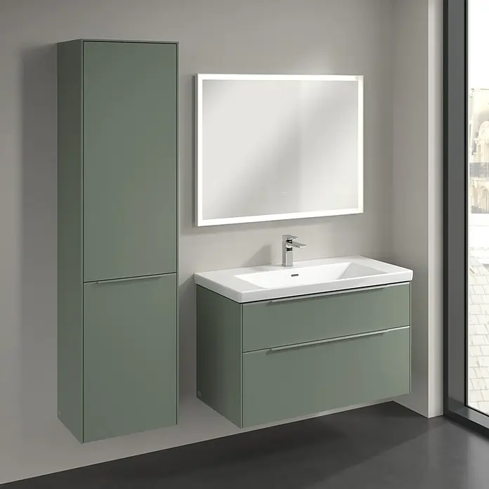 Villeroy & Boch Subway 3.0 Hochschrank - B x T x H: 40 x 36,2 x 171 cm, 1x Klappe mit Wäschekorb, 1x Tür, Soft Green, Farbe Griff: Aluminium glänzend, DIN Anschlag: Links - Badezimmer mit Waschbeckenunterschrank und beleuchtetem Spiegel. Das Waschbecken ist weiß, der Unterschrank ist olivgrün.