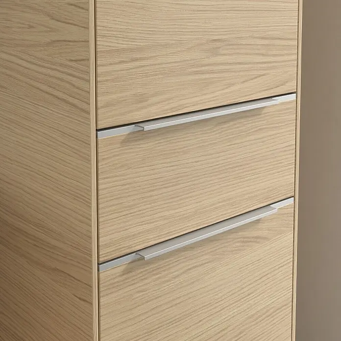 Villeroy & Boch Subway 3.0 Hochschrank - B x T x H: 40 x 36,2 x 171 cm, 1x Schublade, 2x Tür, Nordik oak, Farbe Griff: Aluminium glänzend, DIN Anschlag: Rechts - Detailaufnahme eines hellen Holzkommode mit modernen, silberfarbenen Griffen. Das Möbelstück strahlt schlichte Eleganz aus.