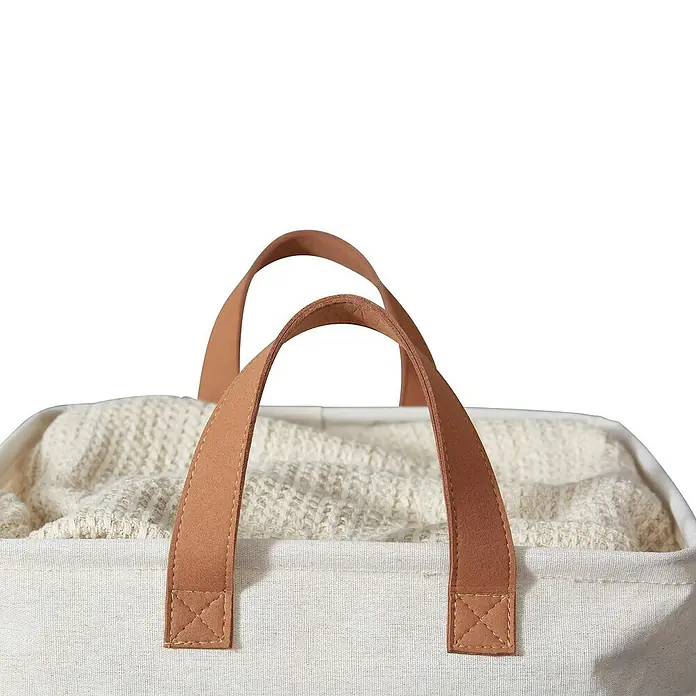 Store It Premium Wäschekorb - L x B x H: 35 x 35 x 58 cm, Beige - Nahaufnahme eines Wäschekorbs aus Stoff mit braunen Ledergriffen, gefüllt mit einer hellen Decke.
