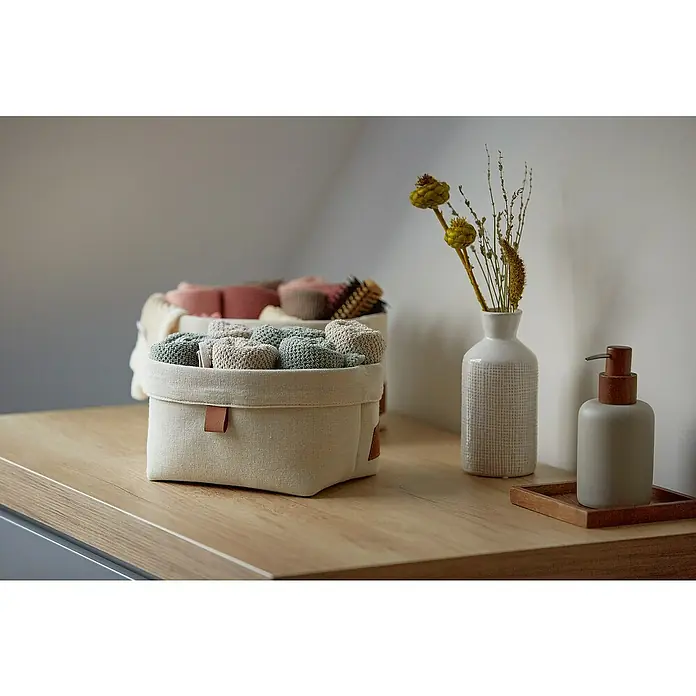 Store It Premium Bad-Aufbewahrungskorb - 22 x 18 x 16 cm, Baumwolle, Beige - Nahaufnahme eines Stoffkorbs mit aufgerollten Handtüchern auf einem Holztisch, neben einer Vase und einer Seifenflasche.