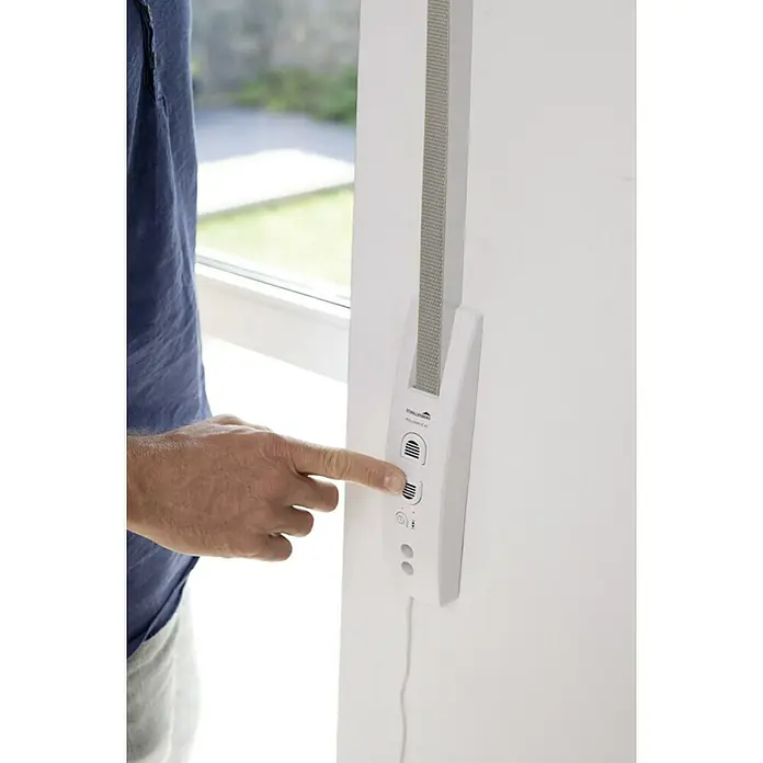 Schellenberg Recogedor de cinta de persiana Rollodrive 45 - Empotrado, Anchura de la correa: 23 mm, Distancia entre orificios: 135 mm - 165 mm - Primer plano de una persona operando un control inteligente de persianas en una pared blanca, destacando el producto innovador.