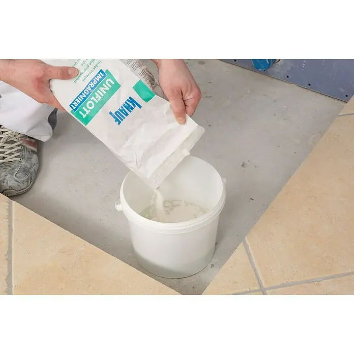 Knauf Fugenspachtel Uniflott imprägniert - 5 kg - Eine Person gießt Knauf Uniflott Imprägniert Fugenfüller in einen weißen Eimer, um ihn für Bauarbeiten vorzubereiten.