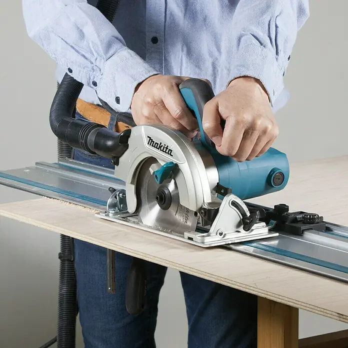 Makita Sierra circular de mano HS6601 - 1.050 W, Diámetro hoja de sierra: 165 mm, Profundidad de corte a 90 °: 54,5 mm - Sierra de inmersión Makita con guía en uso. Cortes precisos para resultados profesionales con una herramienta de alta calidad.