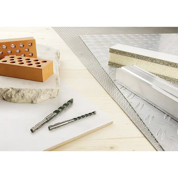 Bosch Universalbohrer - 3 -tlg. - Nahaufnahme von Baumaterialien, darunter Ziegel, Bohrer, Metallplatten und eine Sandwichplatte, die eine Vielfalt an Texturen und Oberflächen zeigt.