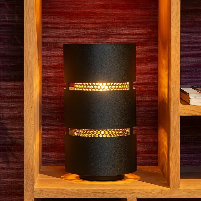 Lucide Rosas Tischleuchte rund - 40 W, Ø x H: 12 x 30 cm, Schwarz/ Gold, Schwarz, E27 - Elegante, schwarze Zylinder-Tischleuchte mit warmem Lichteffekt, platziert auf einem Holzregal, das eine gemütliche Atmosphäre schafft.