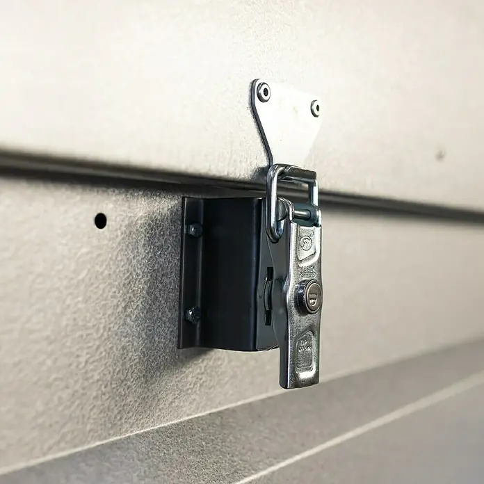 Stema Anhänger BASIC 750 mit Metalldeckel - Nutzlast: 575 kg, Einachser, Kasteninnenmaß: 201 x 108 x 47 cm, Ungebremst - Nahaufnahme eines Metall-Drehriegelverschlusses mit Schlüssel auf einer strukturierten Oberfläche.