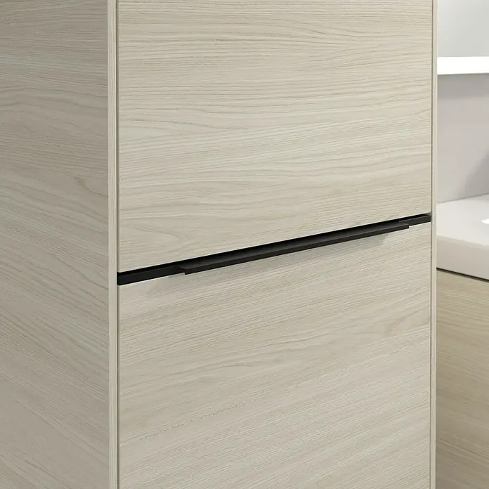 Villeroy & Boch Subway 3.0 Hochschrank - B x T x H: 40 x 36,2 x 171 cm, 1x Klappe mit Wäschekorb, 1x Tür, White Oak, Farbe Griff: Volcano black, DIN Anschlag: Links - Detailaufnahme eines hellen Holzschranks mit einem eleganten, schwarzen Griff. Das schlichte Design des Schranks harmoniert gut mit dem modernen Griff.