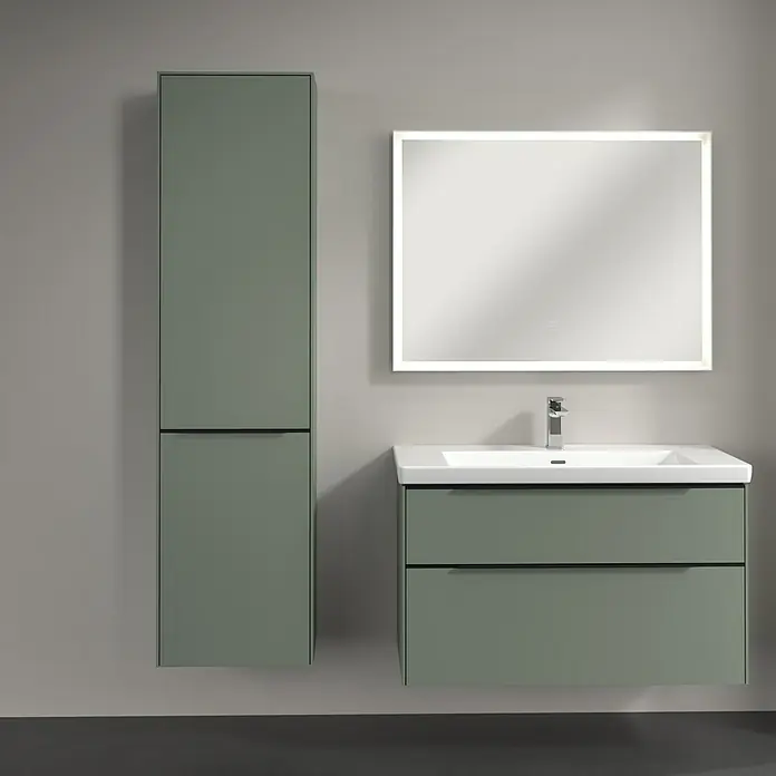 Villeroy & Boch Subway 3.0 Hochschrank - B x T x H: 40 x 36,2 x 171 cm, 1x Klappe mit Wäschekorb, 1x Tür, Soft Green, Farbe Griff: Volcano black, DIN Anschlag: Links - Modernes Badezimmerensemble in Grün mit einem Waschtischunterschrank, einem Hochschrank und einem beleuchteten Spiegel.