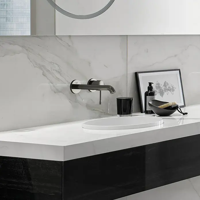 Grohe Essence Waschtischarmatur M - Wandmontage, Hard Graphite, Matt - Modernes Badezimmer mit Armatur an Marmorwand, weißem Aufsatzwaschbecken und schwarzen Akzenten für einen eleganten Look.