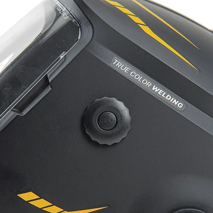 Vito Casco de soldadura - Nivel de protección: 9 ud. - 13 ud., Oscurecimiento ajustable - Primer plano de un casco de soldadura negro con detalles amarillos, una visera transparente y un botón de control para el modo de amolado.