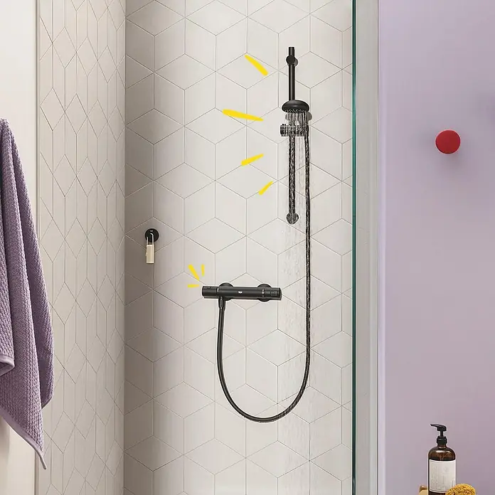 Grohe Start Brausethermostat Precision - Matt, Schwarz - Eine moderne, schwarze Duschgarnitur mit Kopf- und Handbrause vor einer Wand mit geometrischen Fliesen. Das Wasser läuft.