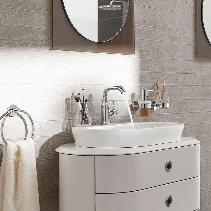 Grohe Essence New Grifo de lavabo - Con varilla de tracción, Cromo, Resplandeciente - Un lavabo de baño moderno con grifo, toallero de aro y varios accesorios que crean un espacio elegante y funcional.