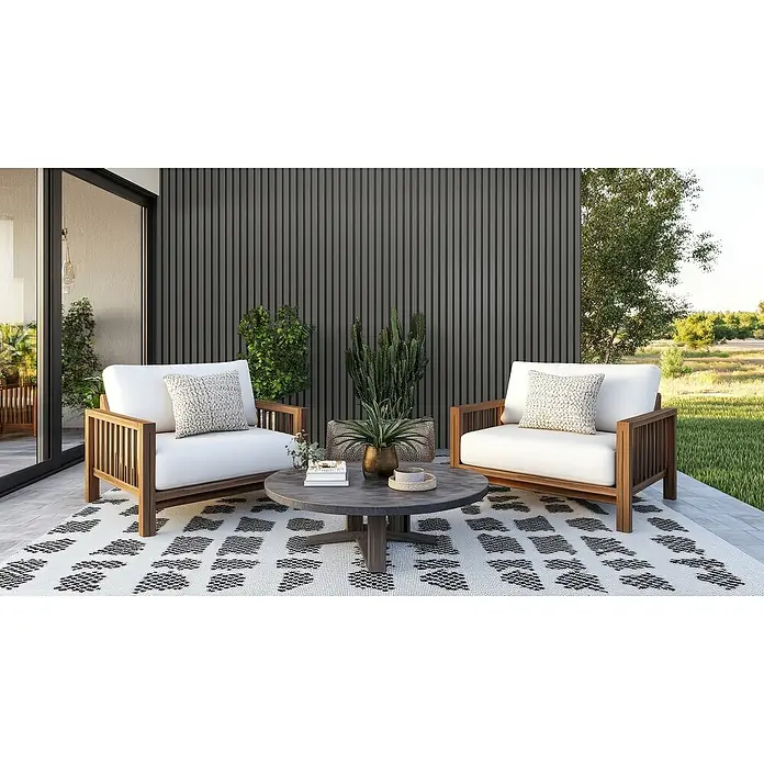 Wandpaneel Outdoor - Grey, WPC, 2.350 x 219 x 26 mm - Einladende Gartengestaltung mit zwei Holzsesseln mit weißen Kissen und einem runden Couchtisch auf einem gemusterten Teppich.