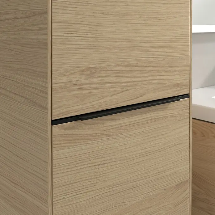 Villeroy & Boch Subway 3.0 Hochschrank - B x T x H: 40 x 36,2 x 171 cm, 1x Klappe mit Wäschekorb, 1x Tür, Nordik oak, Farbe Griff: Volcano black, DIN Anschlag: Links - Detailaufnahme eines hellbraunen Holzschranks mit einem eleganten schwarzen Griff. Das Holz hat eine sichtbare Maserung.