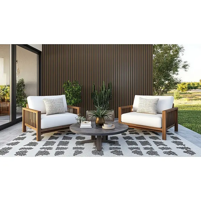 Wandpaneel Outdoor - Dark Brown, WPC, 2.350 x 219 x 26 mm - Einladende Terrasse mit zwei Sesseln und einem runden Tisch auf einem gemusterten Teppich. Die Möbel strahlen Komfort und Stil im Freien aus.