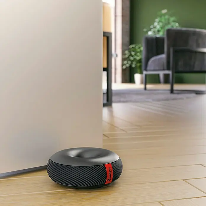 Walteco Türstopper Doornut - Ø x H: 106 x 42 mm, Schwarz - Ein Walteco-Raumlufter in Donutform steht neben einer Tür und sorgt für saubere Luft. Stilvolles Design für ein besseres Raumklima.