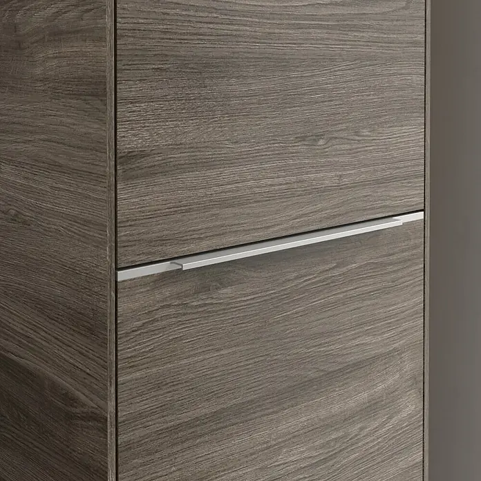 Villeroy & Boch Subway 3.0 Hochschrank - B x T x H: 40 x 36,2 x 171 cm, 1x Klappe mit Wäschekorb, 1x Tür, Stone Oak, Farbe Griff: Aluminium glänzend, DIN Anschlag: Rechts - Nahaufnahme eines modernen Holzschranks mit einem schlanken, silbernen Griff, der seine elegante Linienführung betont.