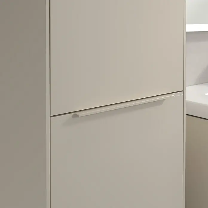 Villeroy & Boch Subway 3.0 Hochschrank - B x T x H: 40 x 36,2 x 171 cm, 1x Klappe mit Wäschekorb, 1x Tür, Cashmere Grey, Farbe Griff: Cashmere Grey, DIN Anschlag: Links - Nahaufnahme eines modernen Badezimmerschranks mit Schubladen in neutralen Farbtönen, der ein schlichtes Design und minimalistische Griffe zeigt.