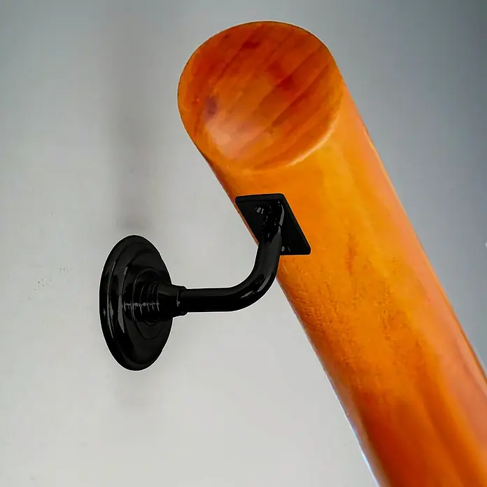 Micel Soporte de pasamanos PMN3 - Zamak, Negro - Primer plano de un poste de pasamanos de madera naranja con un soporte negro en una pared, mostrando un diseño elegante y moderno.