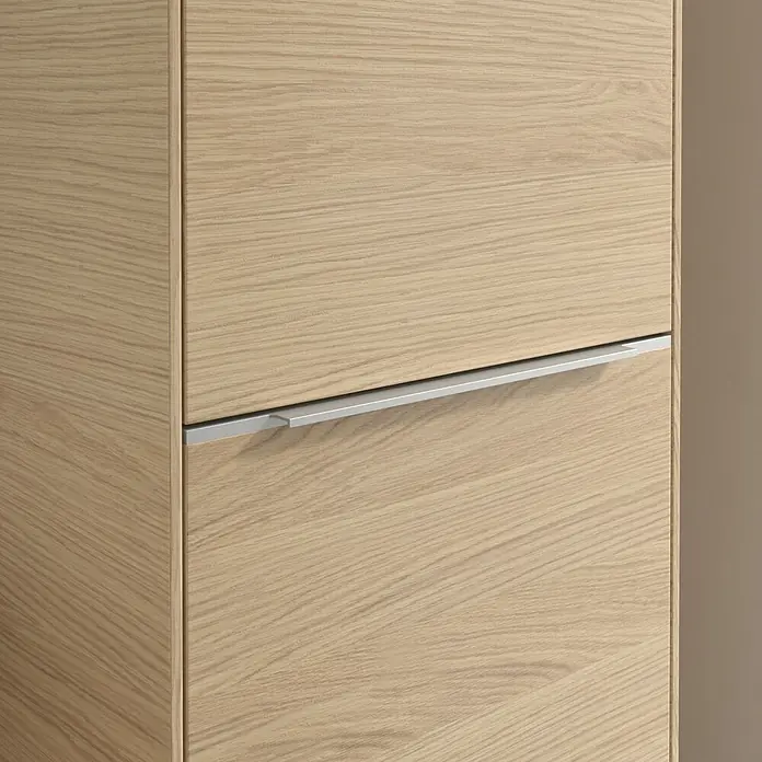 Villeroy & Boch Subway 3.0 Hochschrank - B x T x H: 40 x 36,2 x 171 cm, 1x Klappe mit Wäschekorb, 1x Tür, Nordik oak, Farbe Griff: Aluminium glänzend, DIN Anschlag: Rechts - Detailaufnahme eines modernen Holzschranks mit silbernem Griff. Das schlichte Design und die helle Holzfarbe verleihen dem Möbelstück Eleganz.
