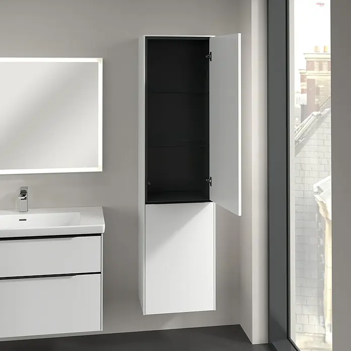 Villeroy & Boch Subway 3.0 Hochschrank - B x T x H: 40 x 36,2 x 171 cm, 1x Klappe mit Wäschekorb, 1x Tür, Pure White, Farbe Griff: Volcano black, DIN Anschlag: Rechts - Ein moderner Badezimmerschrank in Weiß mit einer offenen Tür, die einen Blick auf das schwarze Innere freigibt. Der Schrank hängt an einer grauen Wand.