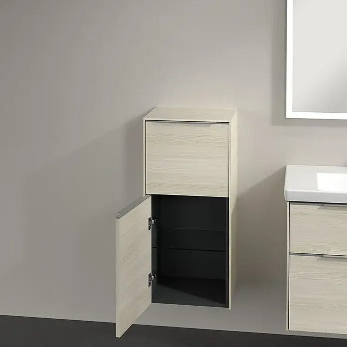 Villeroy & Boch Subway 3.0 Seitenschrank - B x T x H: 40 x 36,2 x 86 cm, White Oak, DIN Anschlag: Links, Farbe Griff: Aluminium glänzend - Badmöbel-Set mit offenem Hochschrank und Unterschrank neben einem beleuchteten Spiegel. Die Holzoberfläche der Badezimmermöbel ist hell.