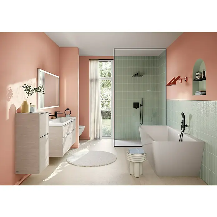 Villeroy & Boch Subway 3.0 Seitenschrank - B x T x H: 40 x 36,2 x 86 cm, White Oak, DIN Anschlag: Links, Farbe Griff: Aluminium glänzend - Ein helles Badezimmer mit einer modernen Badewanne, Dusche, Waschbecken und einem Spiegel. Die Wände sind in einem sanften Pfirsichton gehalten.