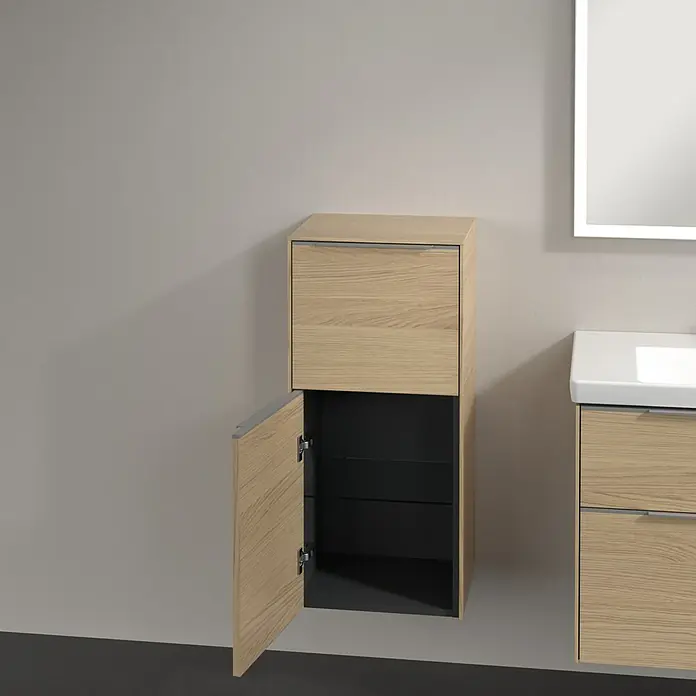 Villeroy & Boch Subway 3.0 Seitenschrank - B x T x H: 40 x 36,2 x 86 cm, Nordik Oak, DIN Anschlag: Links, Farbe Griff: Aluminium glänzend - Ein modernes Badezimmer mit einem Hängeunterschrank in Holzoptik, dessen Tür geöffnet ist und Einblick in das schwarze Innere gibt.