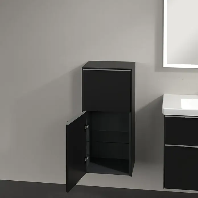 Villeroy & Boch Subway 3.0 Seitenschrank - B x T x H: 40 x 36,2 x 86 cm, Volcano Black, DIN Anschlag: Links, Farbe Griff: Aluminium glänzend - Ein dunkler Badezimmerschrank mit offener Tür, der zwei Regale zeigt. Ein Waschbecken und ein beleuchteter Spiegel sind im Hintergrund zu sehen.