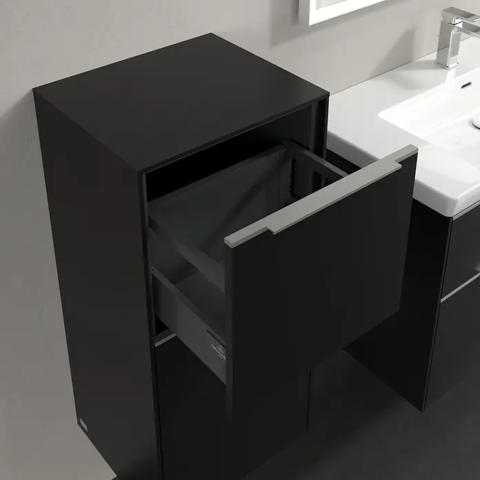 Villeroy & Boch Subway 3.0 Seitenschrank - B x T x H: 40 x 36,2 x 86 cm, Volcano Black, DIN Anschlag: Links, Farbe Griff: Aluminium glänzend - Schwarzer Badezimmerschrank mit offener Schublade neben einem weißen Waschbecken mit Armatur.