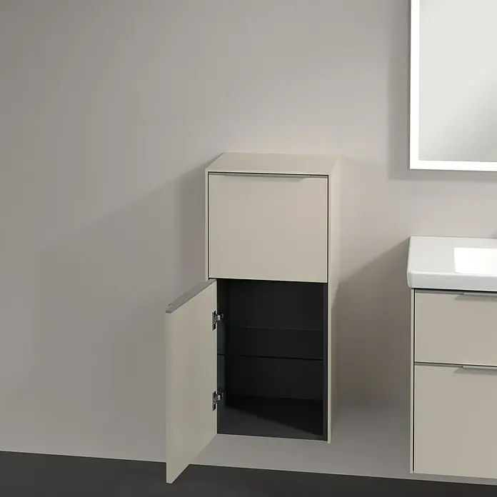 Villeroy & Boch Subway 3.0 Seitenschrank - B x T x H: 40 x 36,2 x 86 cm, Cashmere Grey, DIN Anschlag: Links, Farbe Griff: Aluminium glänzend - Das Bild zeigt einen modernen Badezimmerschrank in Beige mit einer offenen Tür, die Einblick in die dunklen Regale gibt, neben einem beleuchteten Spiegel.