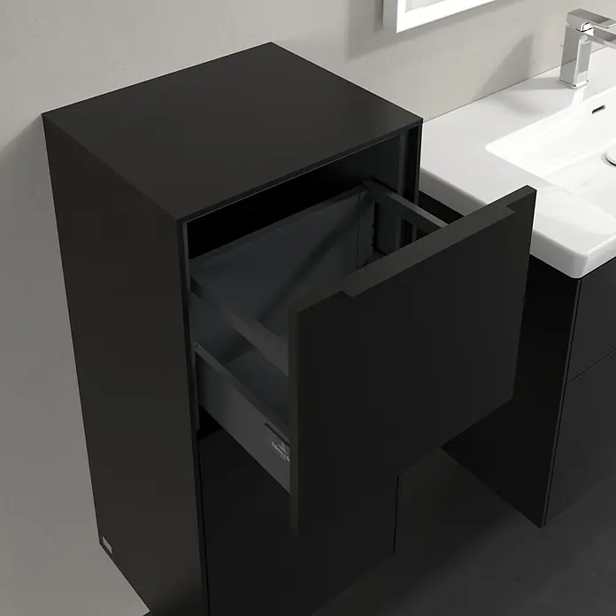Villeroy & Boch Subway 3.0 Seitenschrank - B x T x H: 40 x 36,2 x 86 cm, Volcano Black, DIN Anschlag: Links, Farbe Griff: Volcano Black - Schwarzer Badezimmerschrank mit offener Schublade neben einem weißen Waschbecken mit Wasserhahn.