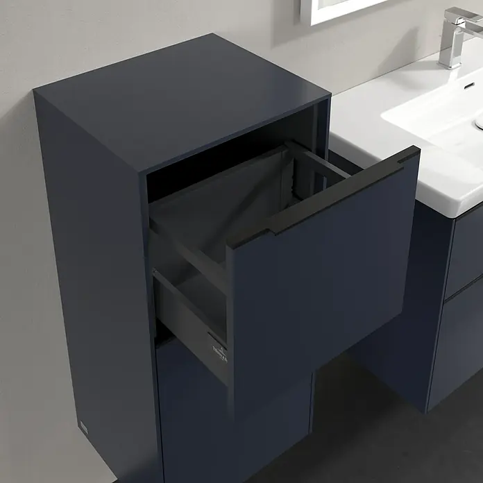 Villeroy & Boch Subway 3.0 Seitenschrank - B x T x H: 40 x 36,2 x 86 cm, Marine Blue, DIN Anschlag: Links, Farbe Griff: Volcano Black - Abbildung eines Badezimmerunterschranks in dunklem Farbton mit einer offenen Schublade, die das Innere zeigt. Das Waschbecken ist neben dem Unterschrank platziert.