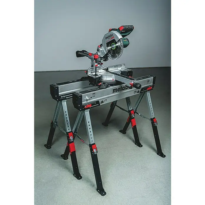 Metabo Arbeitsblock-Set - Stahl, 2 -tlg. - Das Bild zeigt eine Metabo Kappsäge auf einem stabilen Untergestell. Die Säge ist silberfarben mit grünen und roten Akzenten.
