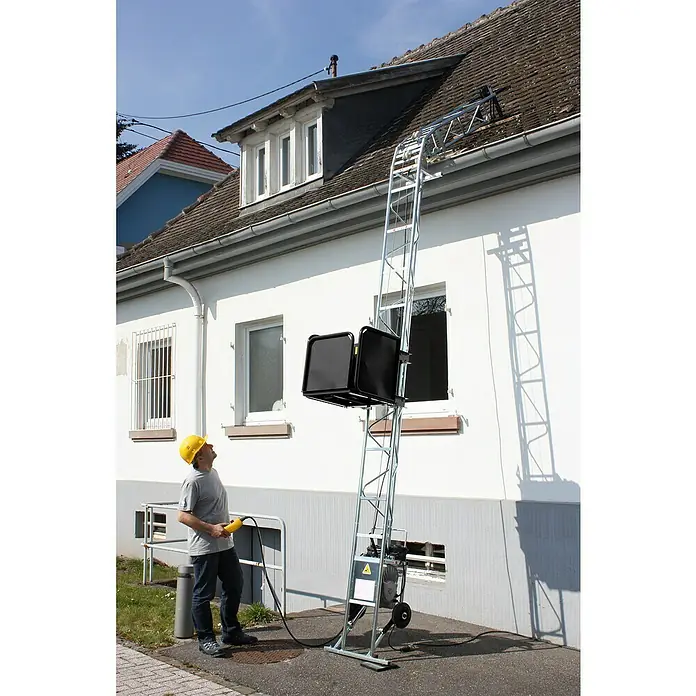 Haemmerlin Castor Steel Bauaufzug 150/20 Dachdecker - Länge: 10 m, Stahl, Ausführungseigenschaft: Dachdeckerpritsche - Ein Mann mit Schutzhelm bedient eine Materialseilwinde vor einem Haus, die Lasten aufs Dach befördern kann.