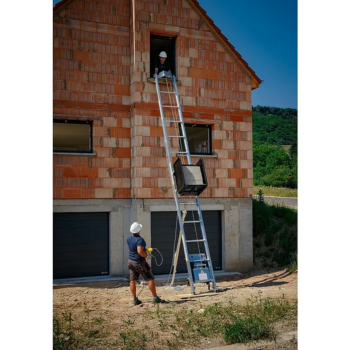 Haemmerlin Maxial Bauaufzug Excellium 200/30 Dachdecker - Länge: 10,5 m, Aluminium, Ausführungseigenschaft: Dachdeckerpritsche - Ein Bauaufzug wird von einem Arbeiter am Boden bedient, während ein anderer im Fenster des Hauses steht, um Baumaterialien entgegenzunehmen.